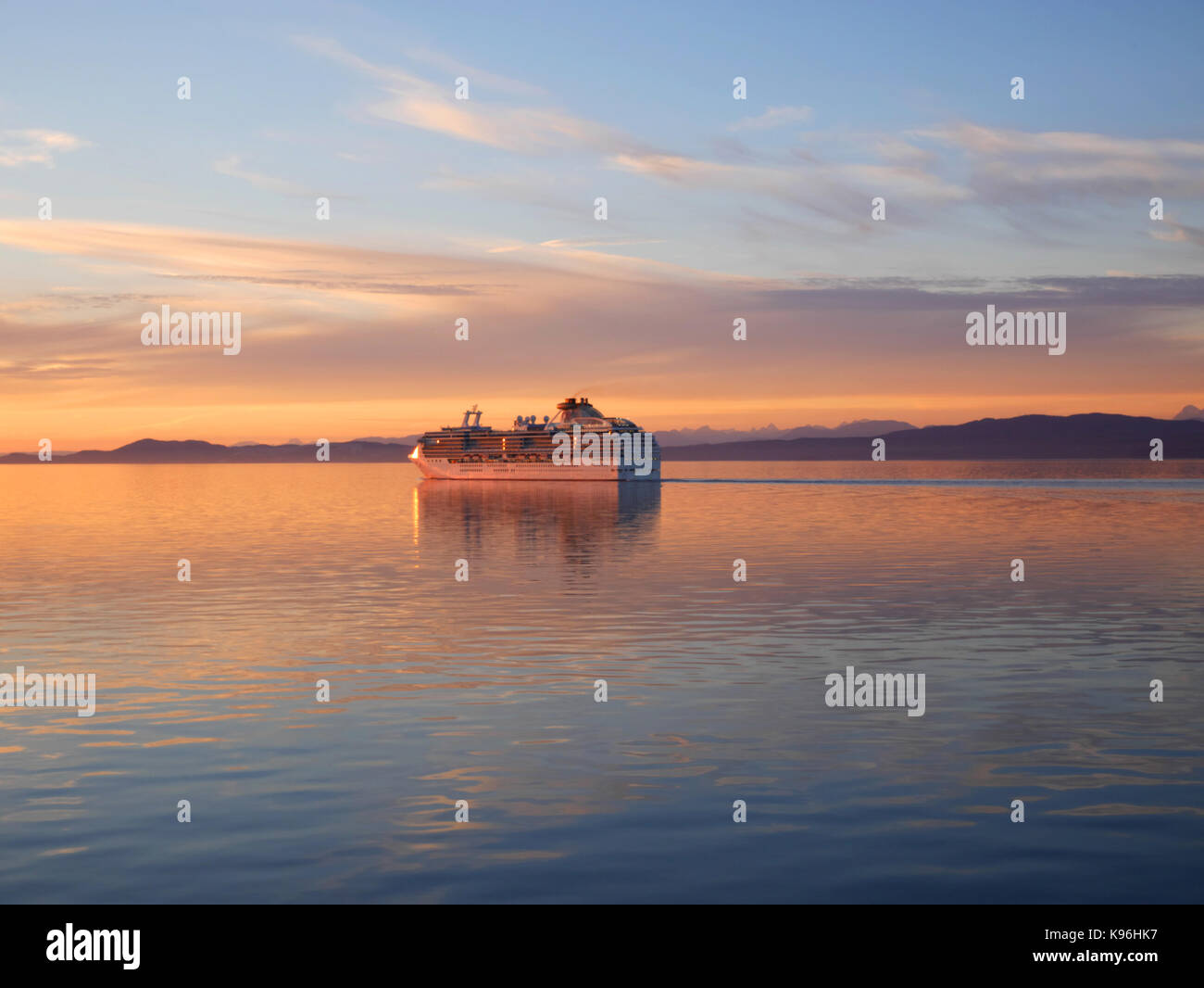 The sun sets behind the cruise liner 'Coral Princess' as she sails into the Straits of Georgis from Vancouver, BC, Canada. Stock Photo