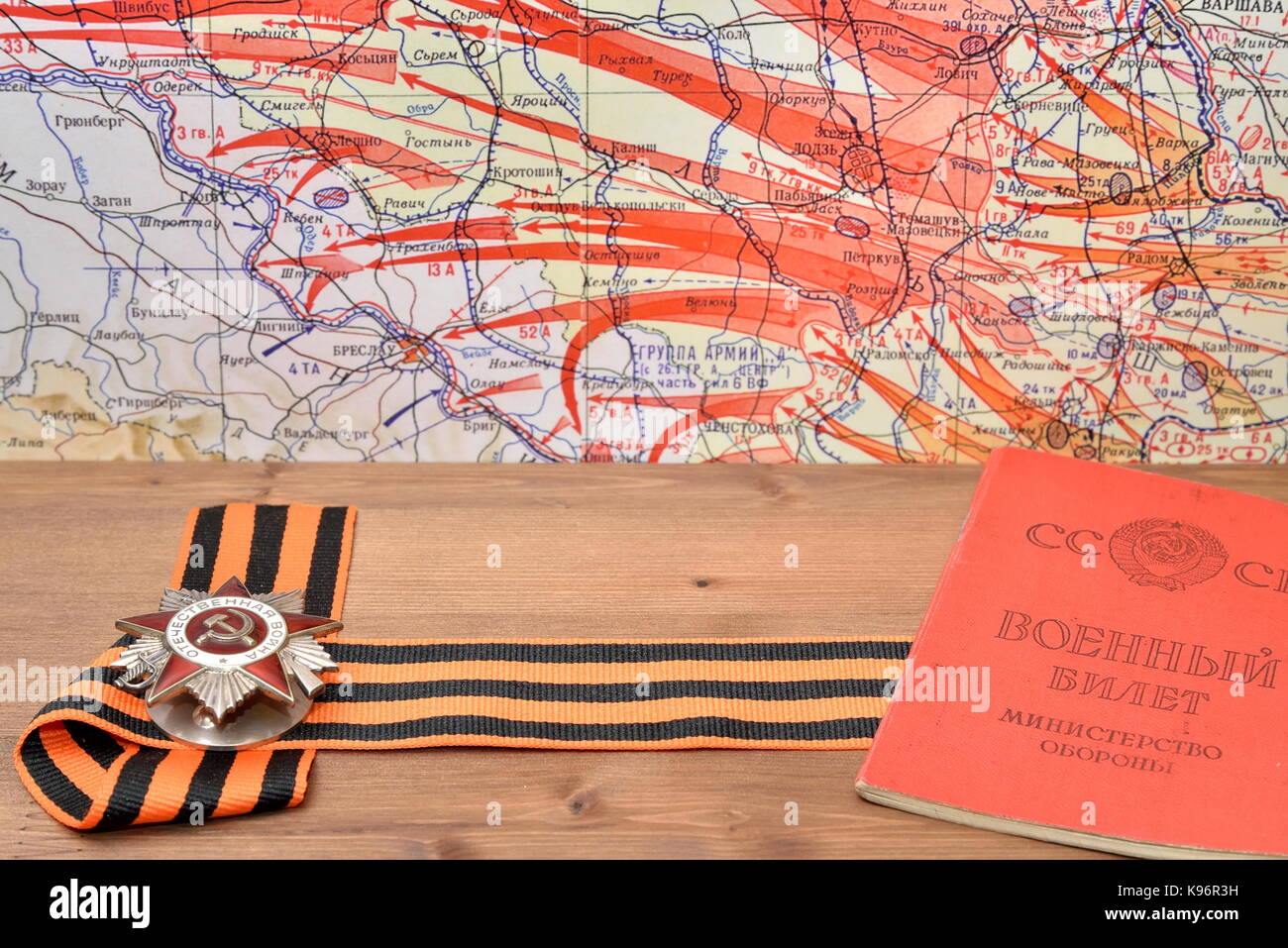 Order of the Patriotic War in St. George's bow, and the old Soviet military ticket lying on the wooden table against the background of military maps o Stock Photo