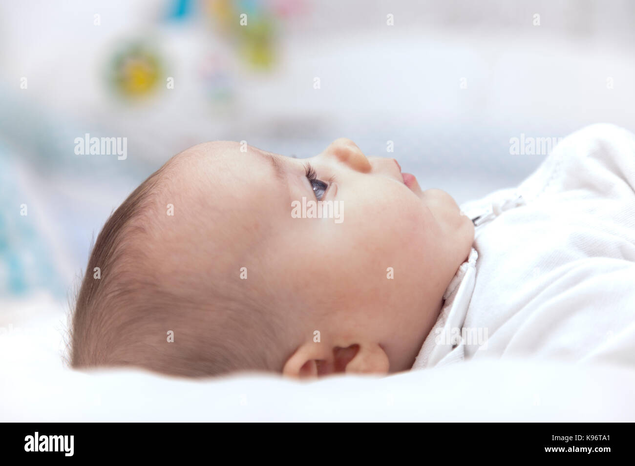 BABY RESTING. Beautiful and little baby boy resting over the bed. Side face view. Stock Photo