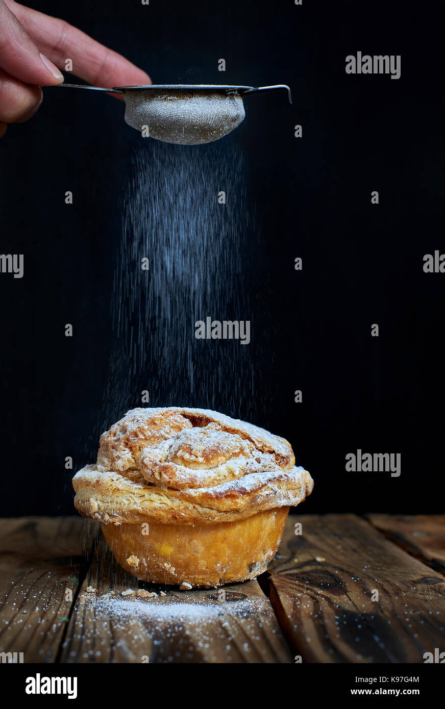 Hand sprinkling powdered sugar on a Mirliton cupcake, traditional sweet