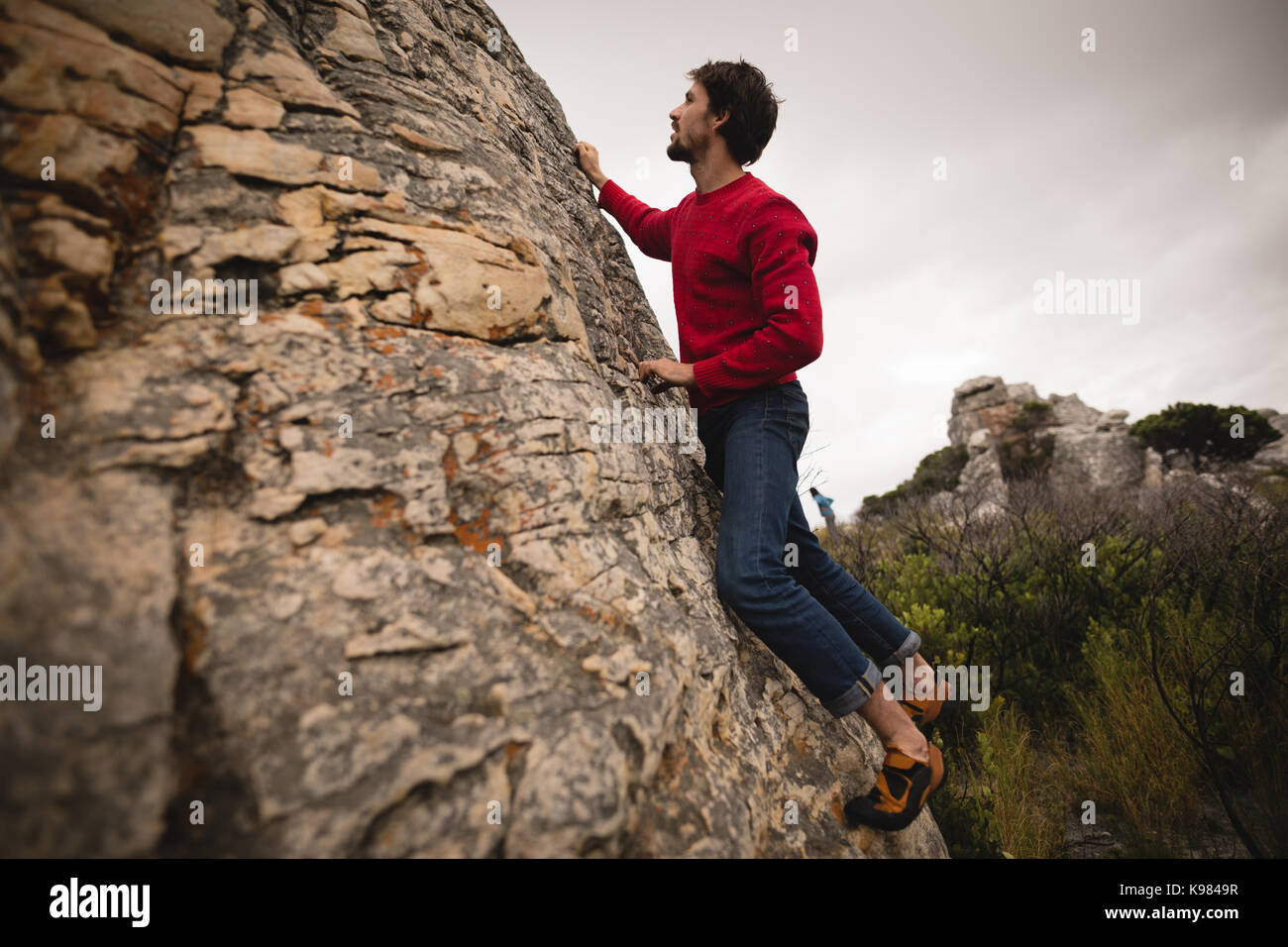 Determined man climbing cliff on a sunny day Stock Photo