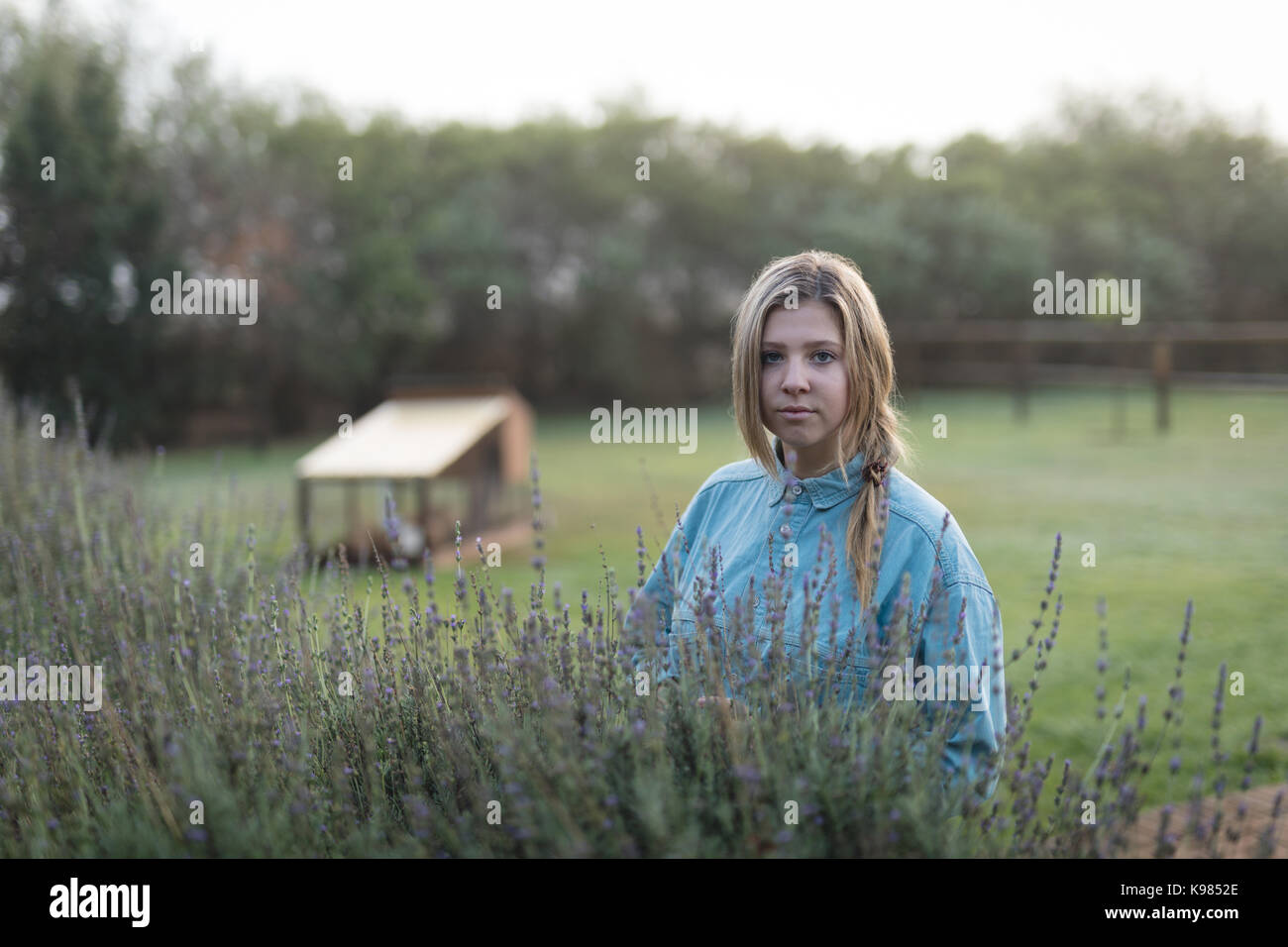 Portrait of young woman standing by plants at park Stock Photo - Alamy