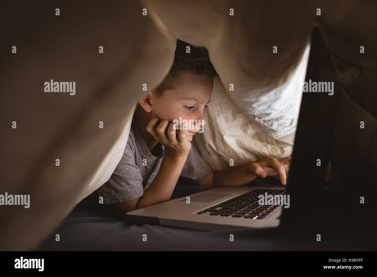 Cute boy using laptop in bedroom Stock Photo - Alamy