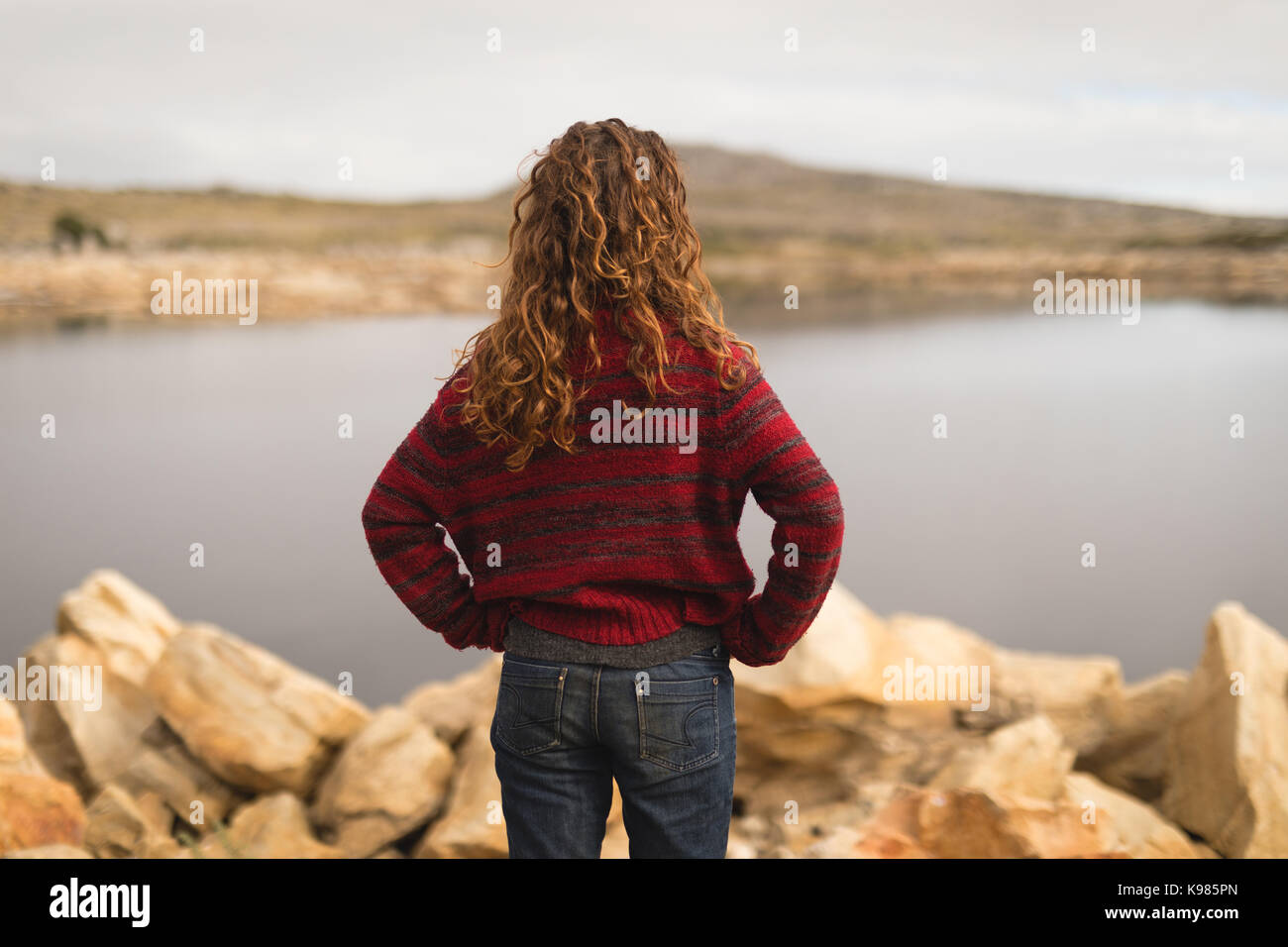Rear view of woman standing near lakeside Stock Photo - Alamy