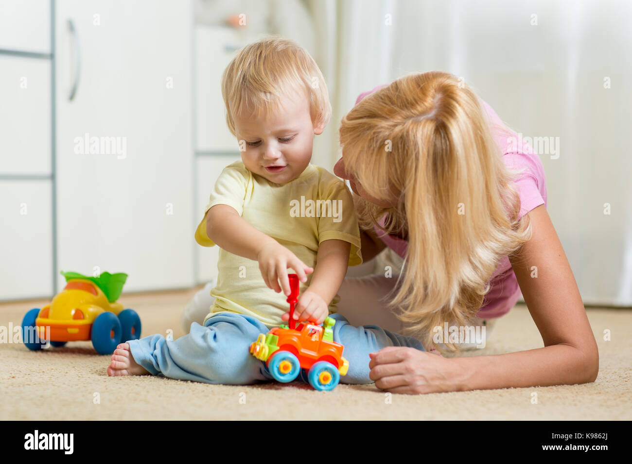 Child boy and his mother repair toy car at home Stock Photo