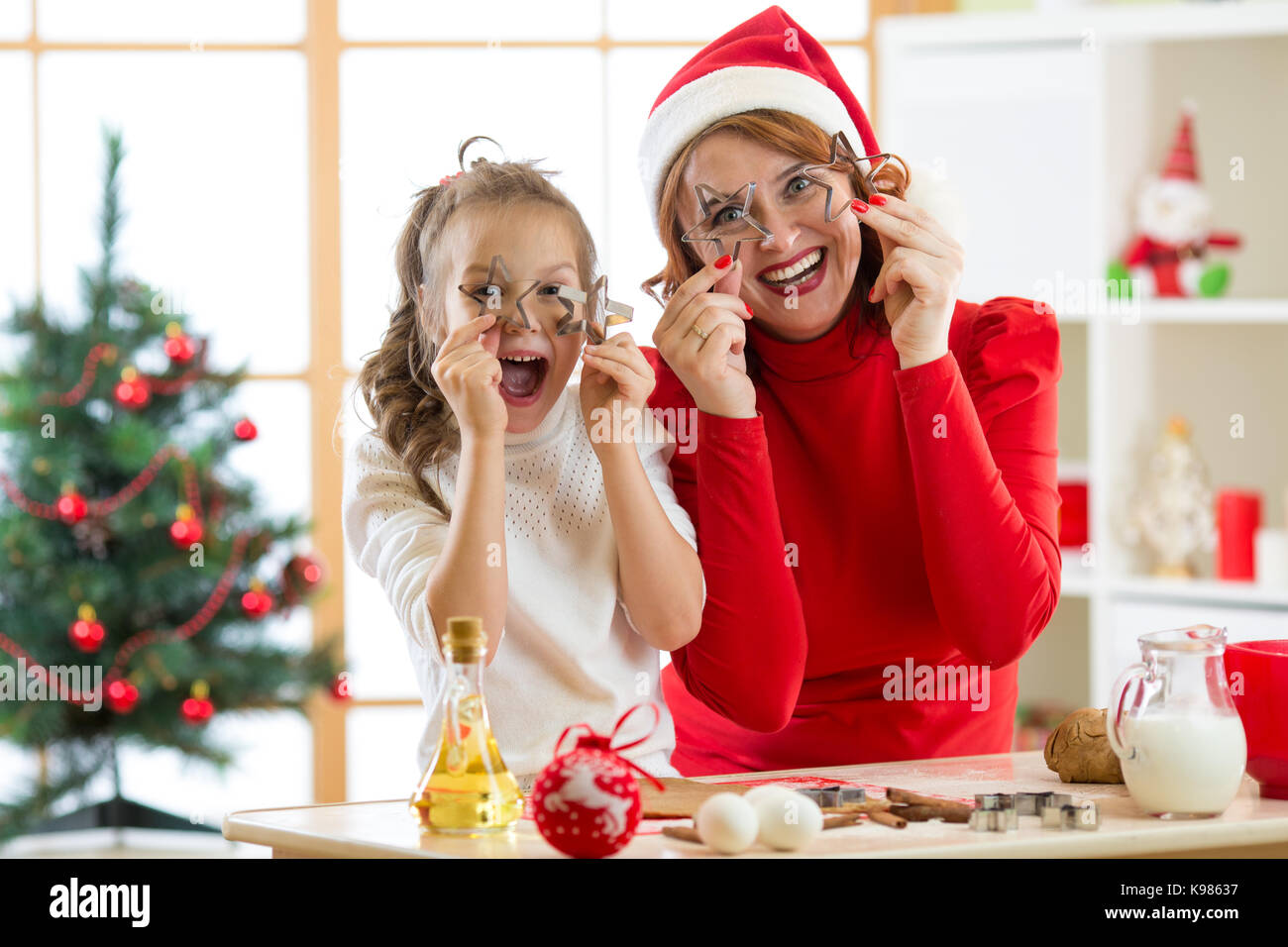 happy family mother and child have a fun preparing the dough. Woman and daughter bake christmas cookies in festival decorated room Stock Photo