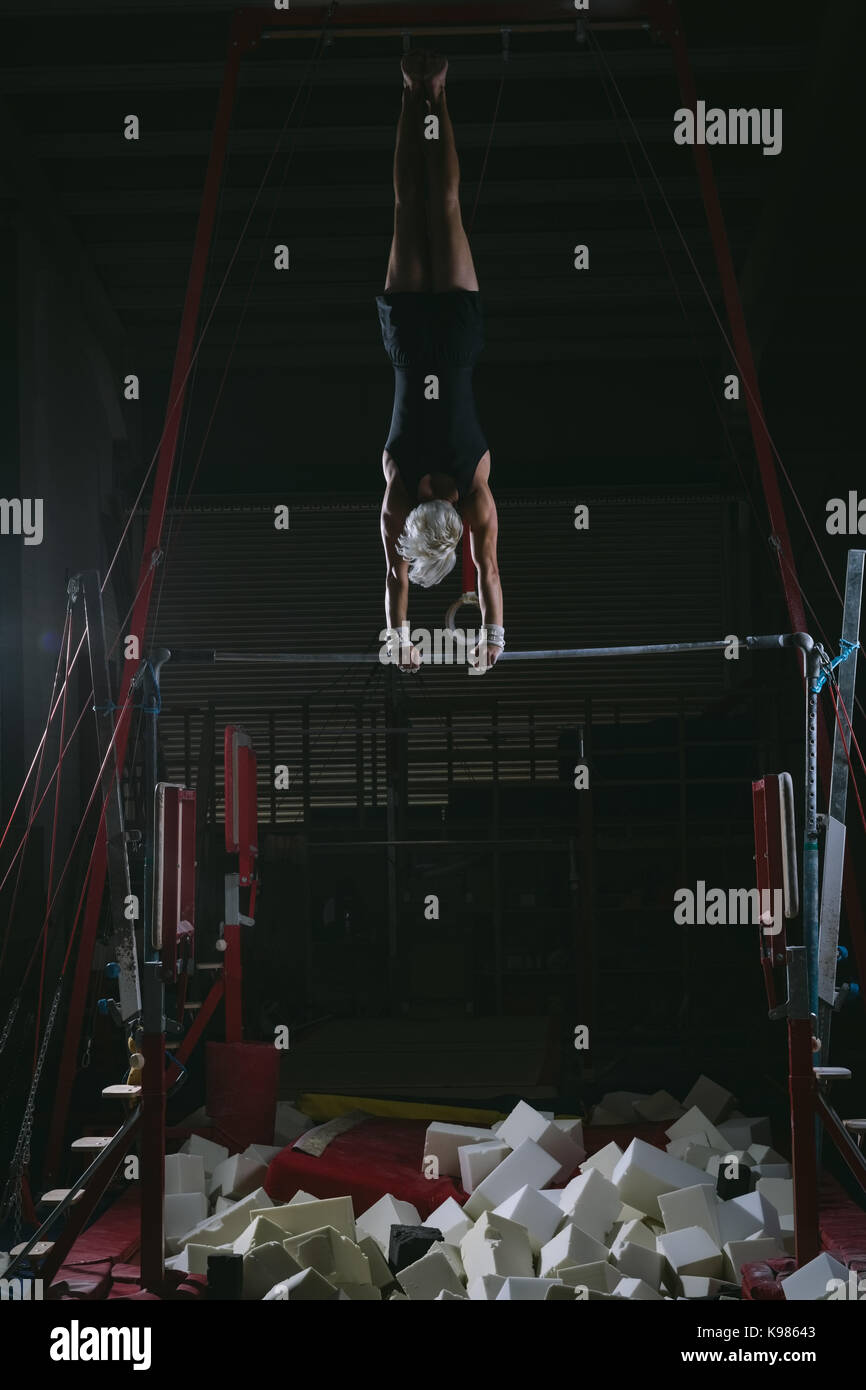 Male gymnast practicing gymnastics on the horizontal bar in the gym
