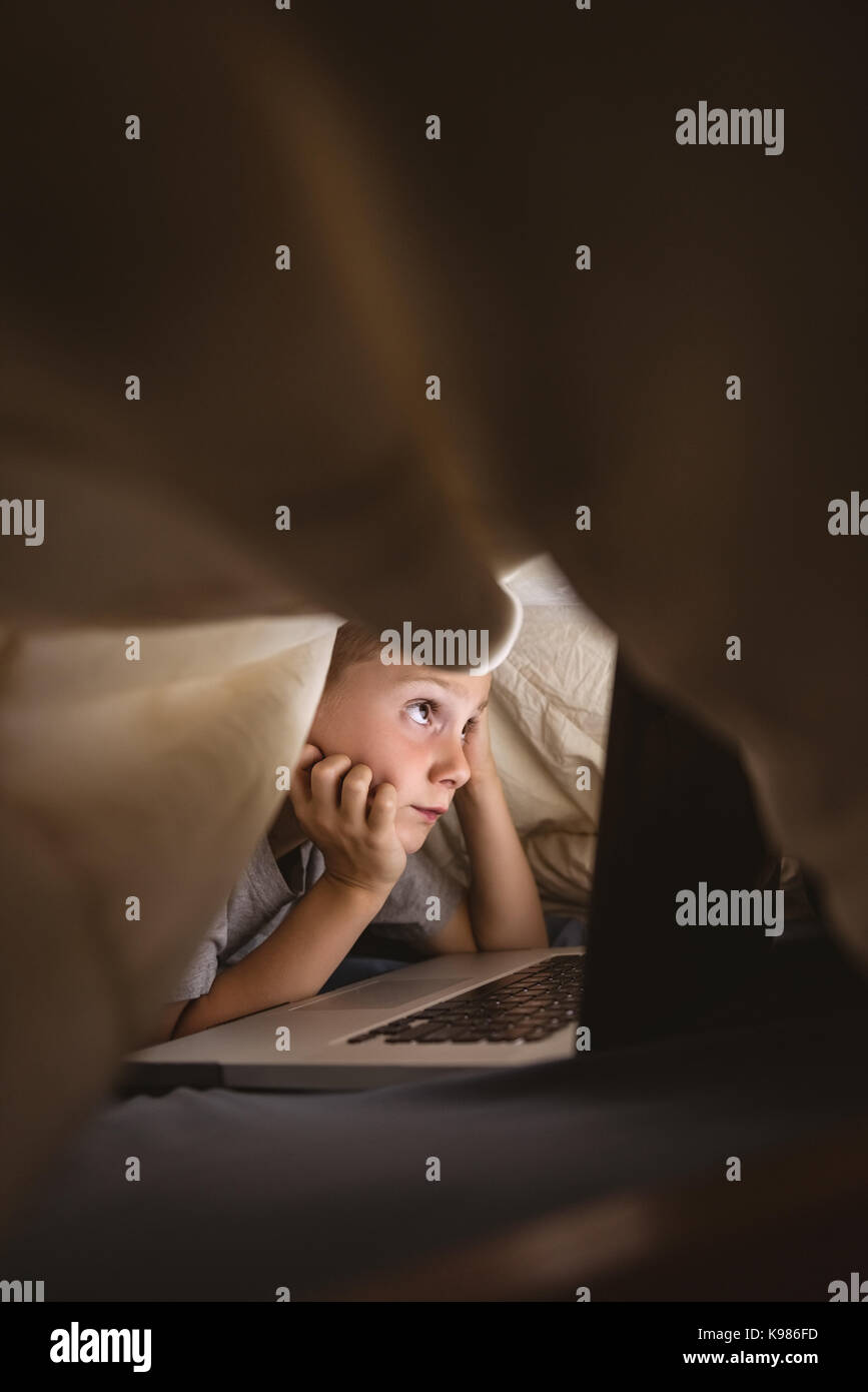 Cute boy using laptop in bedroom Stock Photo - Alamy