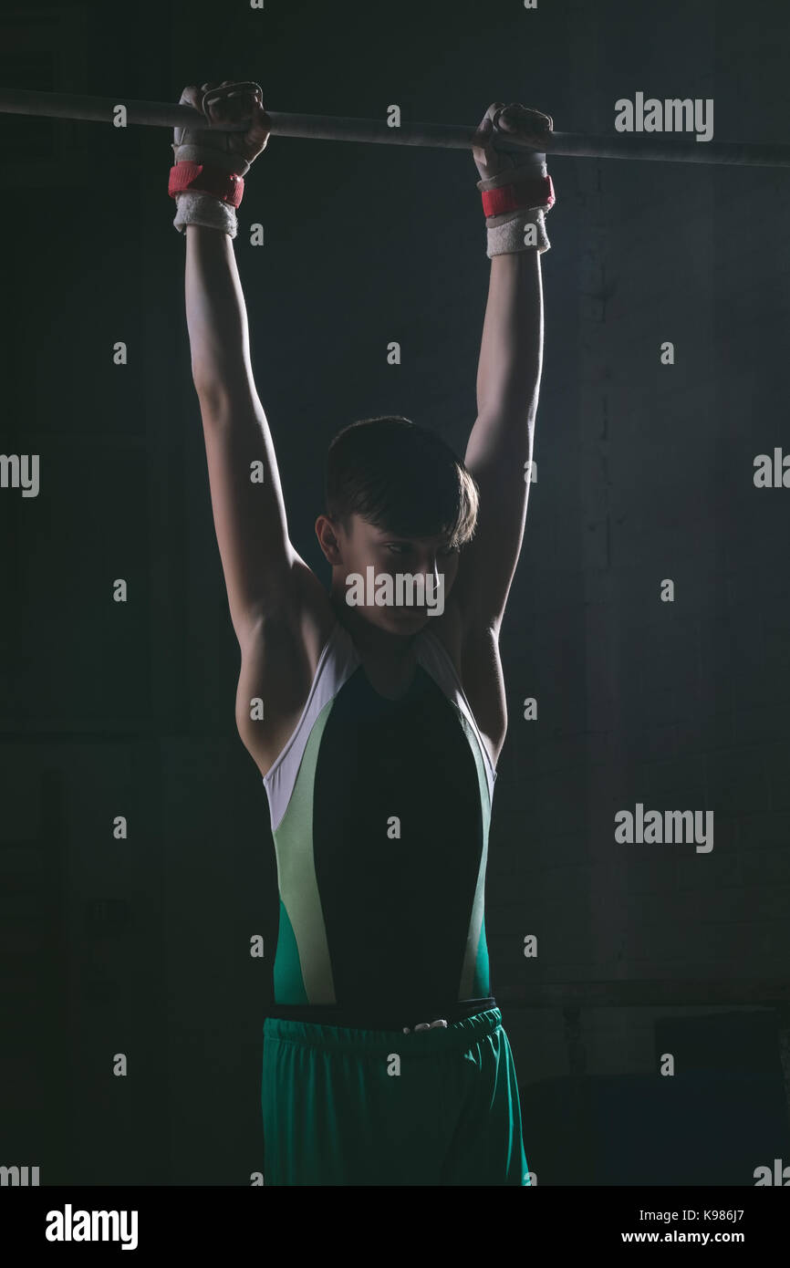 Male gymnast practicing gymnastics on the horizontal bar in the gym