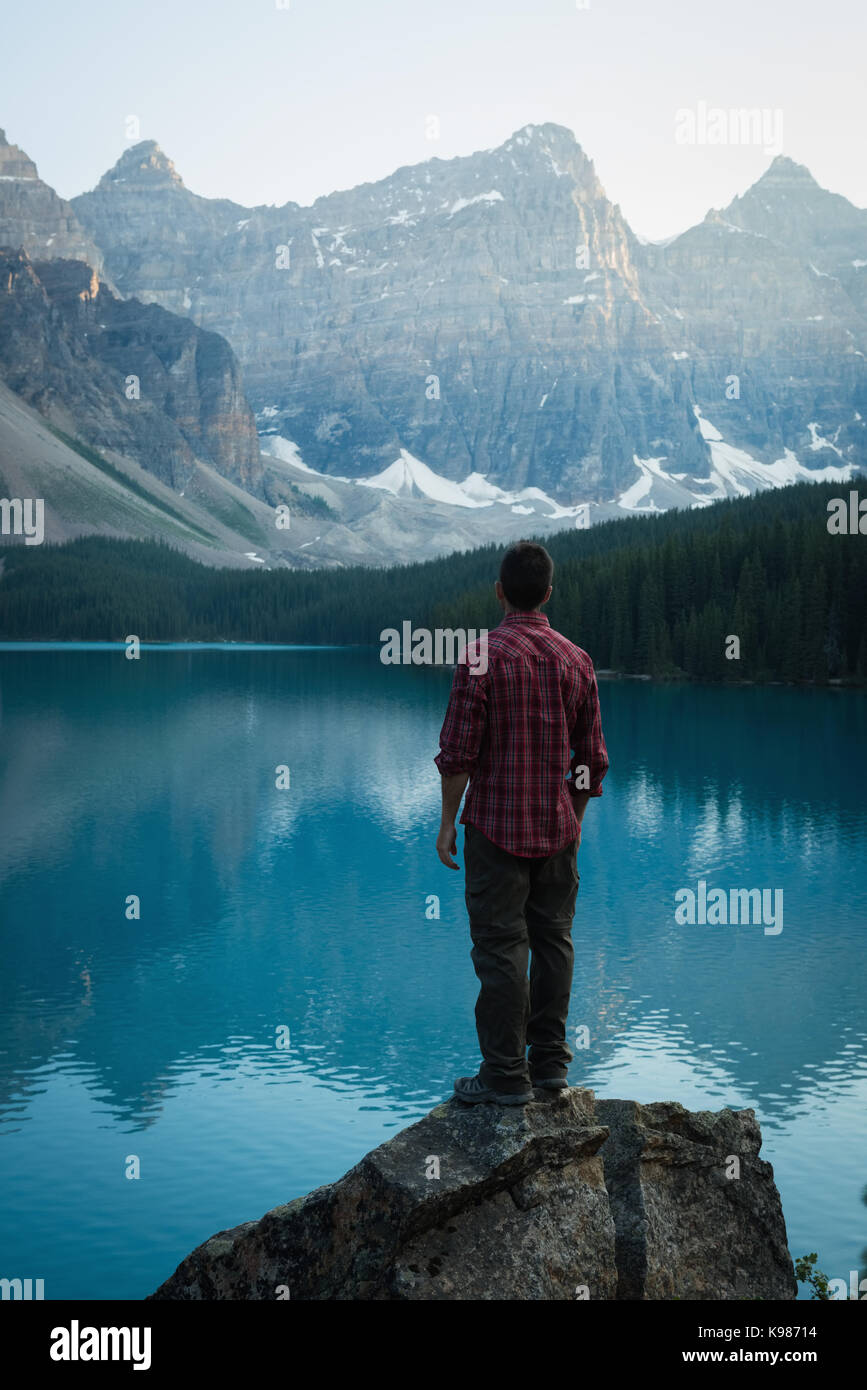 Rear view of man standing near lake side on a sunny day Stock Photo