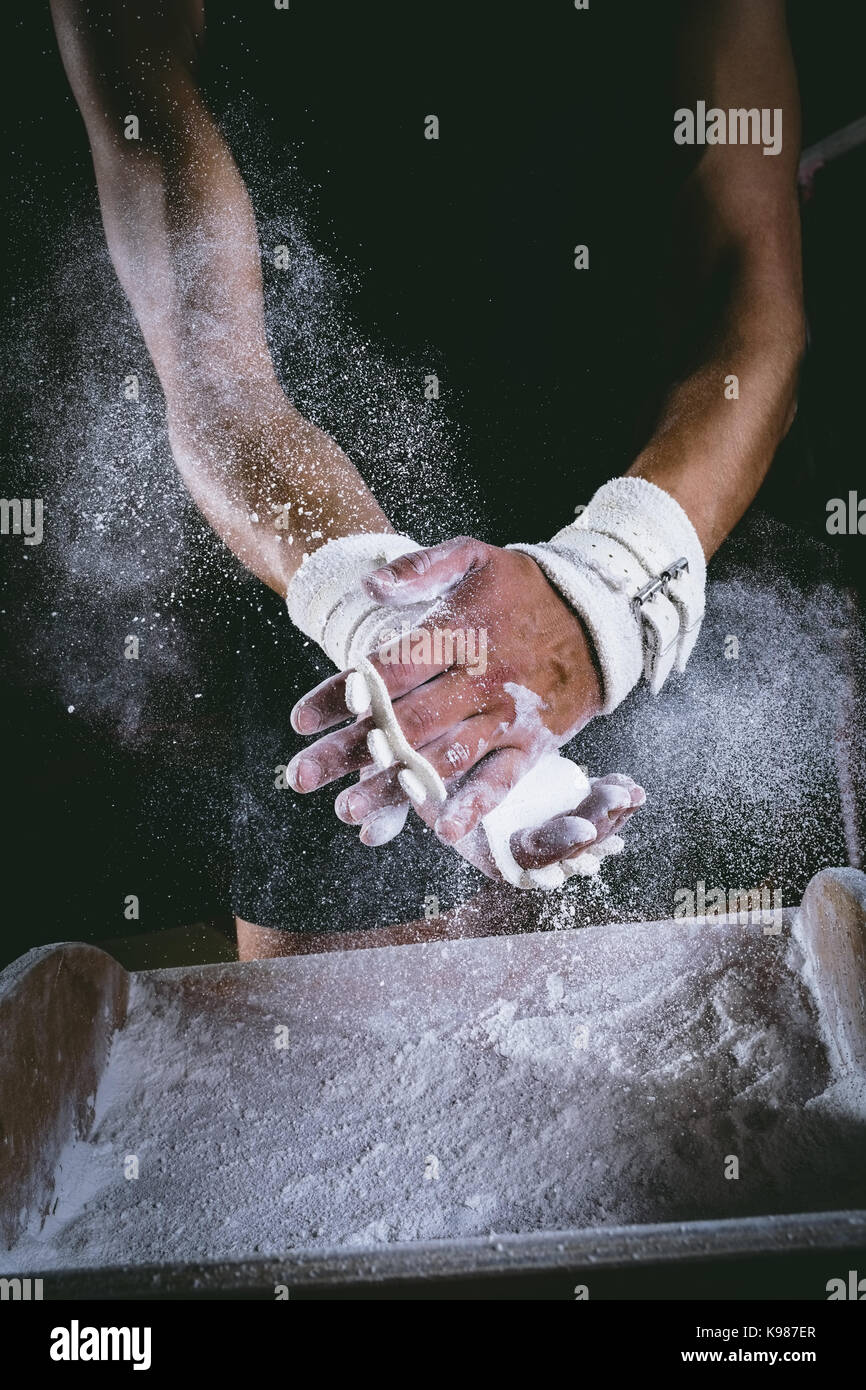 Midsection of male gymnast rubbing her hands with chalk powder Stock