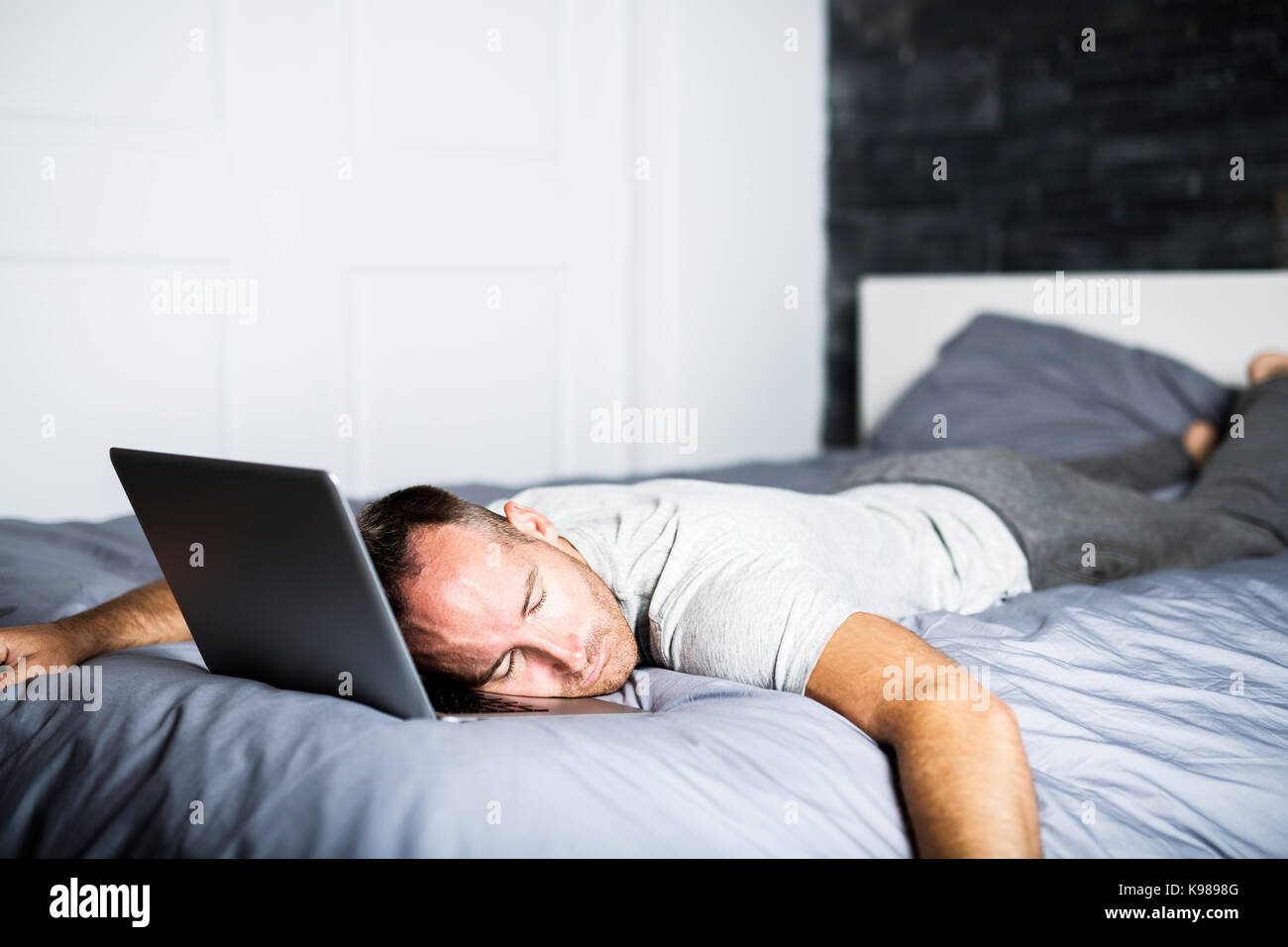 A man sleeping over laptop computer in bed Stock Photo Alamy