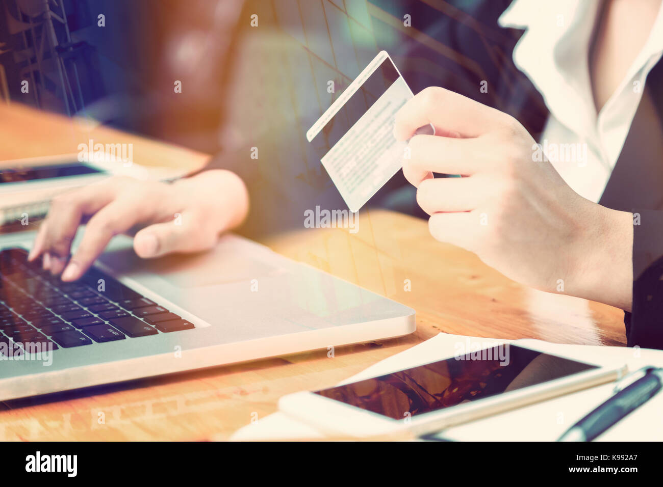 female hand of business woman holding credit card making purchase online with window reflection and lens flare effect, good for business ecommerce con Stock Photo