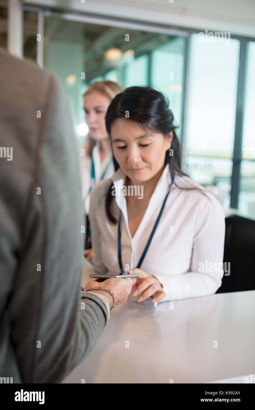 Cropped Businesswoman Showing Smart Phone To Receptionist At Air Stock Photo