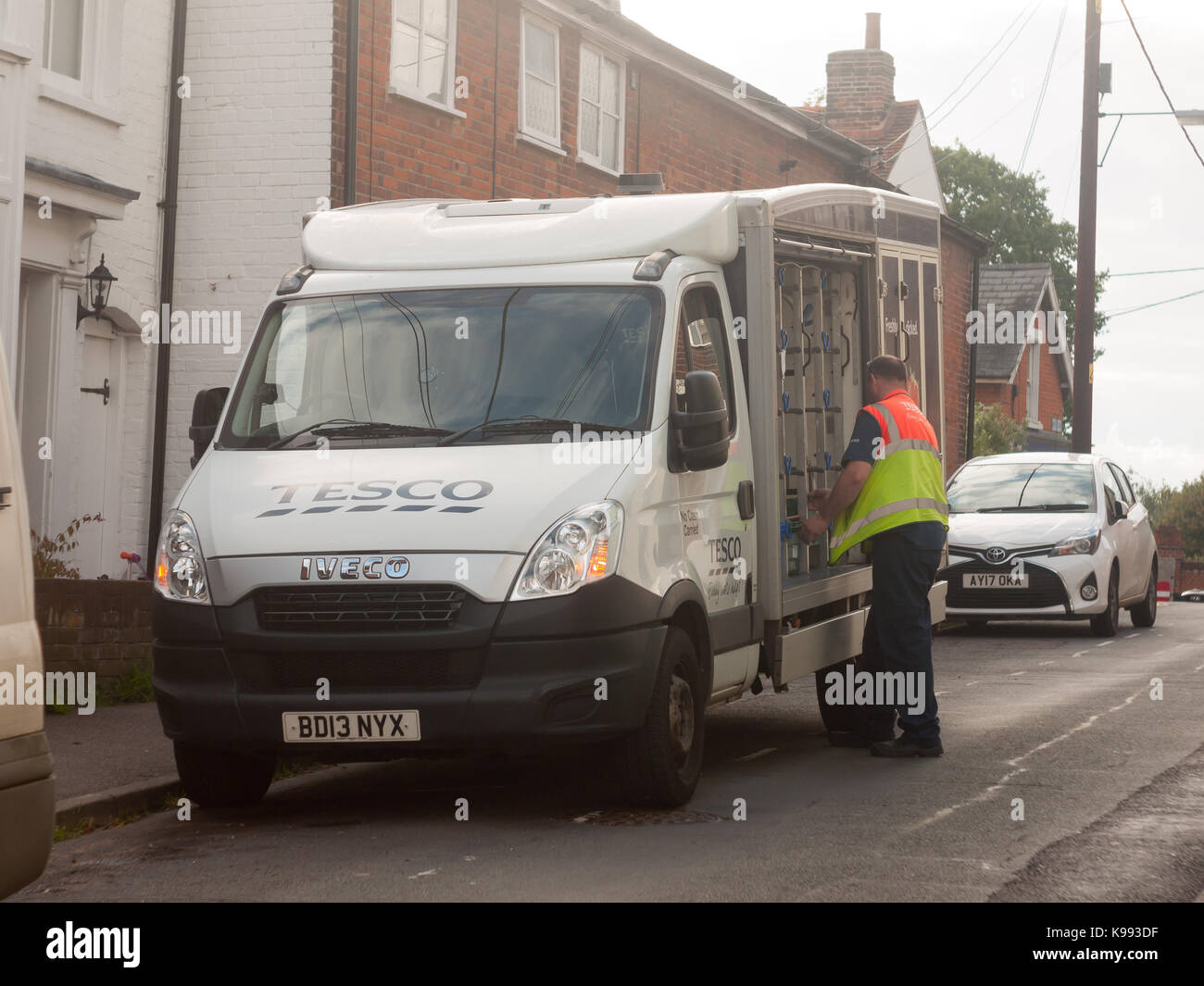 tesco supermarket food delivery can with worker getting crates; England