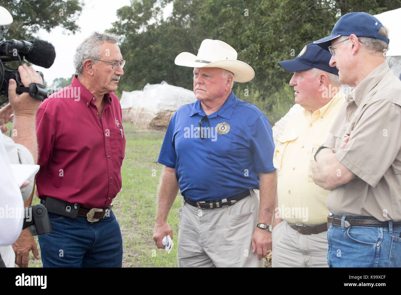 El Campo, USA. 21st Sep, 2017. U.S. Secretary of Agriculture Sonny Perdue (yellow shirt), House Agriculture Chairman Mike Conaway (tan) and Texas Agriculture Commissioner Sid Miller (blue) tour cotton farms ravaged by Hurricane Harvey three weeks ago. In red is cotton buyer Johnny Ropolo. Credit: Bob Daemmrich/Alamy Live News Stock Photo