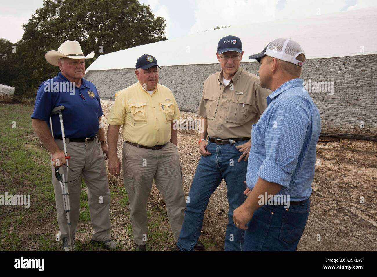 El Campo, USA. 21st Sep, 2017. U.S. Secretary of Agriculture Sonny Perdue (yellow shirt), House Agriculture Chairman Mike Conaway (tan) and Texas Agriculture Commissioner Sid Miller (blue) tour cotton farms ravaged by Hurricane Harvey three weeks ago. At right is farmer Keith Cresta. Credit: Bob Daemmrich/Alamy Live News Stock Photo