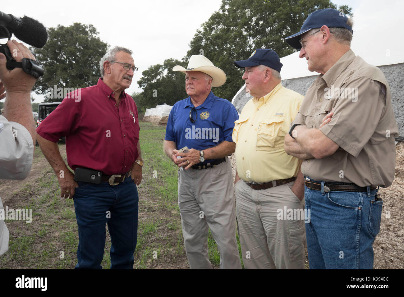 El Campo, USA. 21st Sep, 2017. U.S. Secretary of Agriculture Sonny Perdue (yellow shirt), House Agriculture Chairman Mike Conaway (tan) and Texas Agriculture Commissioner Sid Miller (blue) tour cotton farms ravaged by Hurricane Harvey three weeks ago. In red is cotton buyer Johnny Ropolo. Credit: Bob Daemmrich/Alamy Live News Stock Photo