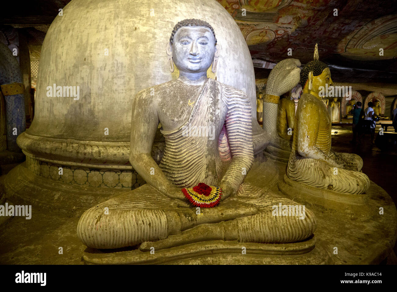 Dambulla Sri Lanka Dambulla Cave Temples - Cave II  Maharaja Viharaya Statue Of Seated Buddha Showing Dhyana Mudra Gesture Of Meditation With Flower Offering In Hands In Front Of Dagoba Stock Photo