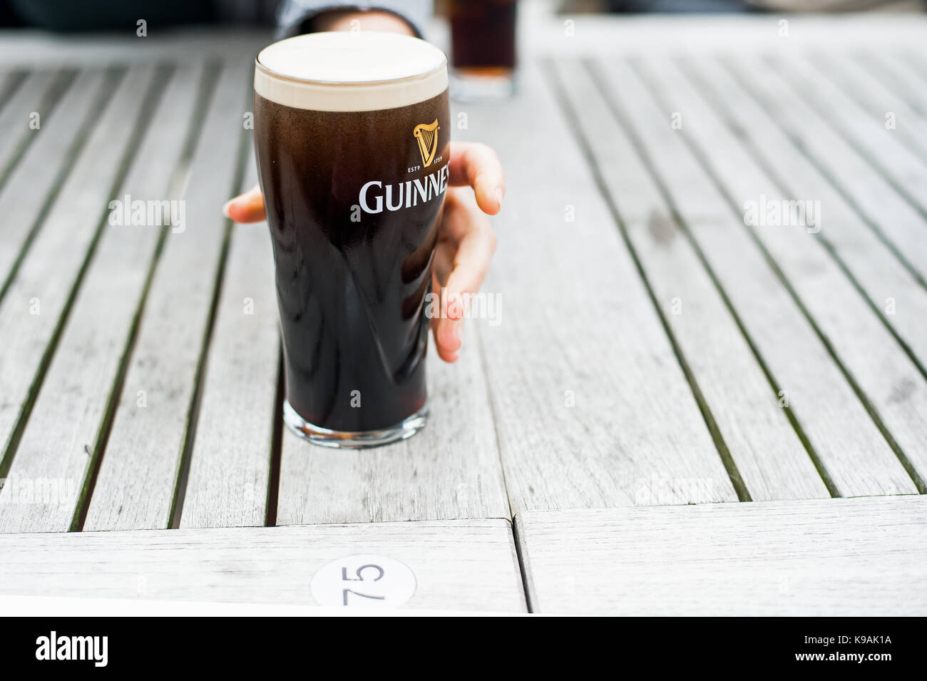 A pint glass of Guinness about to be grabbed. Stock Photo