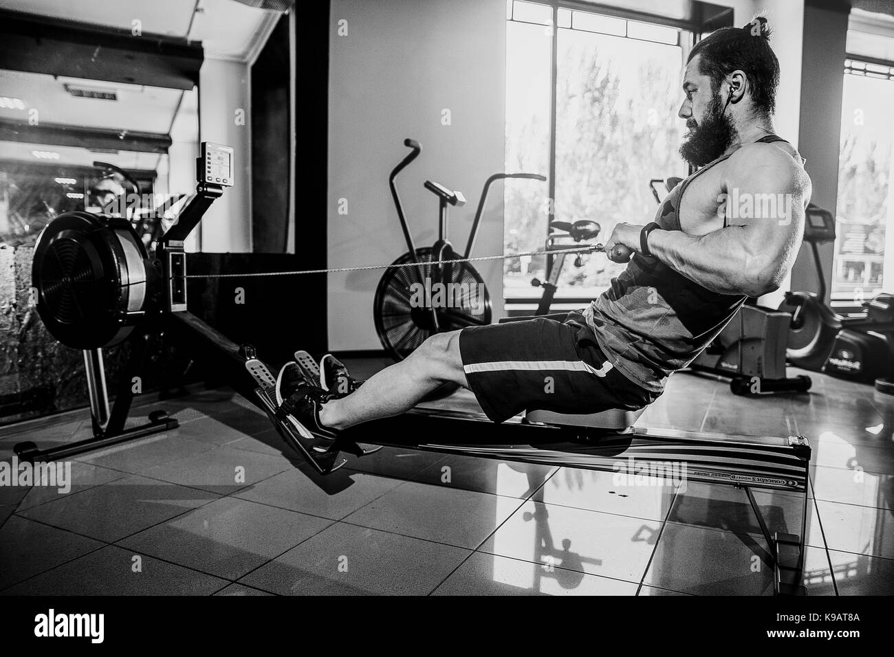 Muscular fit man using rowing machine at gym Stock Photo