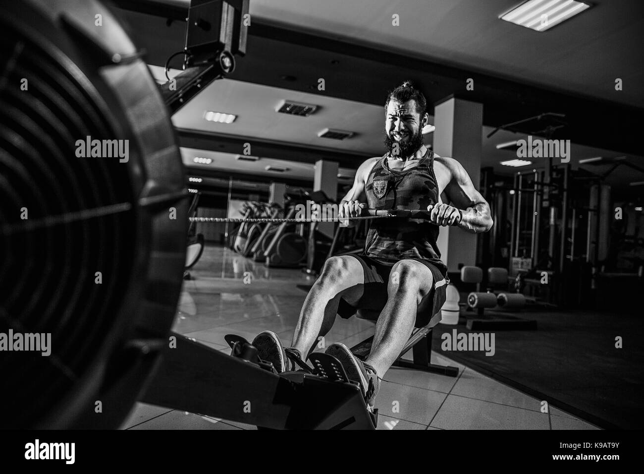 Muscular fit man using rowing machine at gym Stock Photo