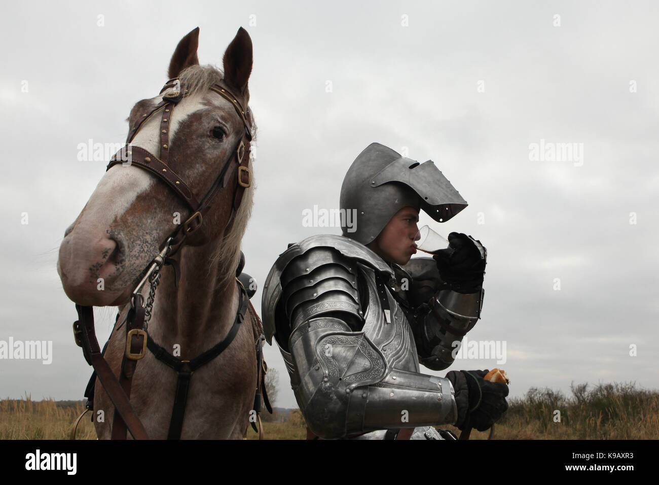 Czech actor Michal Bednář dressed as a medieval knight drinks and eats next to his horse during the filming of the new German film 'Die Ritter' ('The Knights') directed by Carsten Gutschmidt by order of ZDF in Milovice in Central Bohemia, Czech Republic in 23 October 2013. Stock Photo