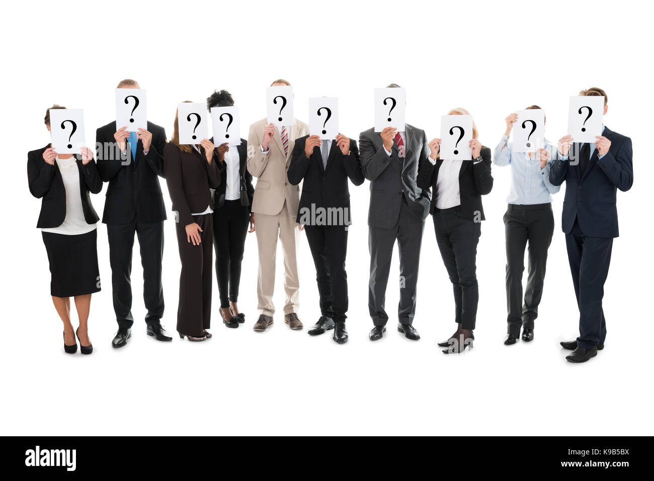 Full length of business team hiding faces with question mark signs against white background Stock Photo
