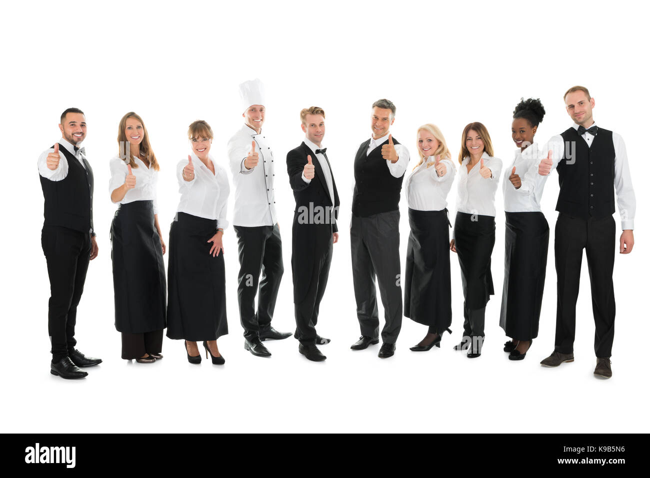 Full length portrait of confident restaurant staff standing in row against white background Stock Photo