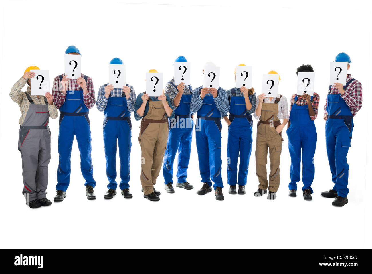Full length of construction workers hiding faces with question mark signs against white background Stock Photo
