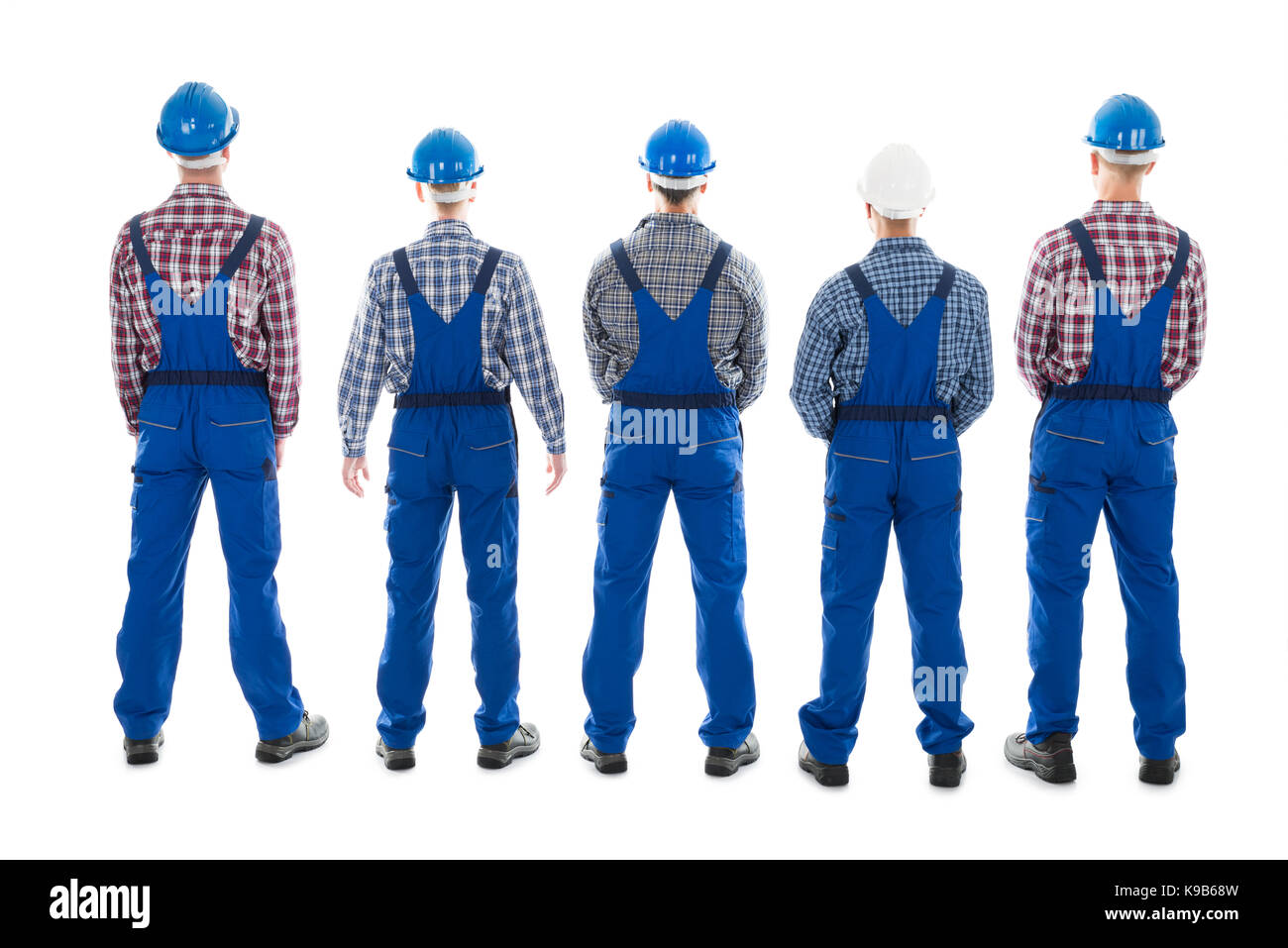 Full length rear view of male carpenters standing in row against white background Stock Photo