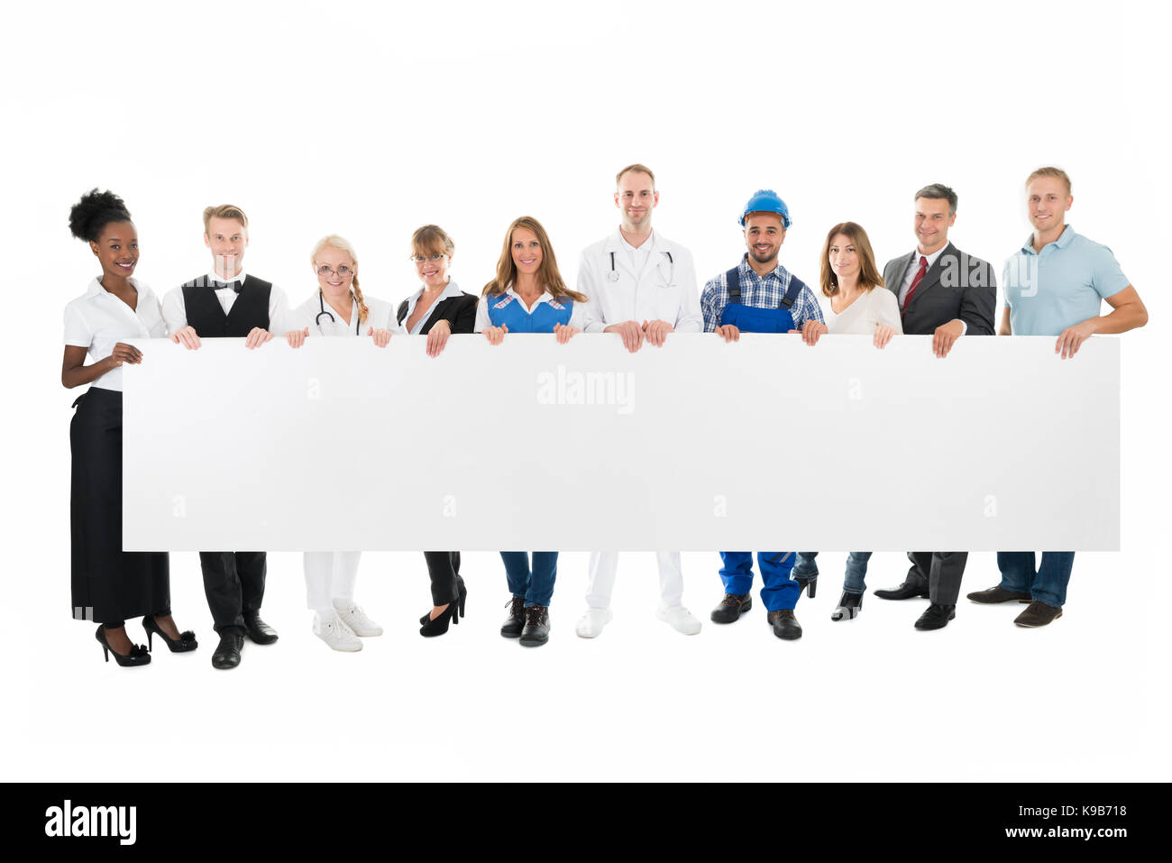 Group portrait of people with various occupations holding blank billboard against white background Stock Photo