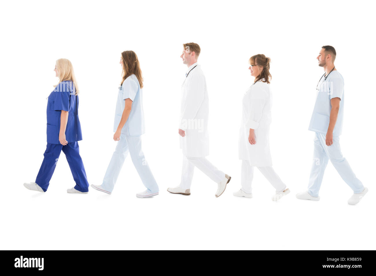 Full length side view of medical professionals walking in row against white background Stock Photo