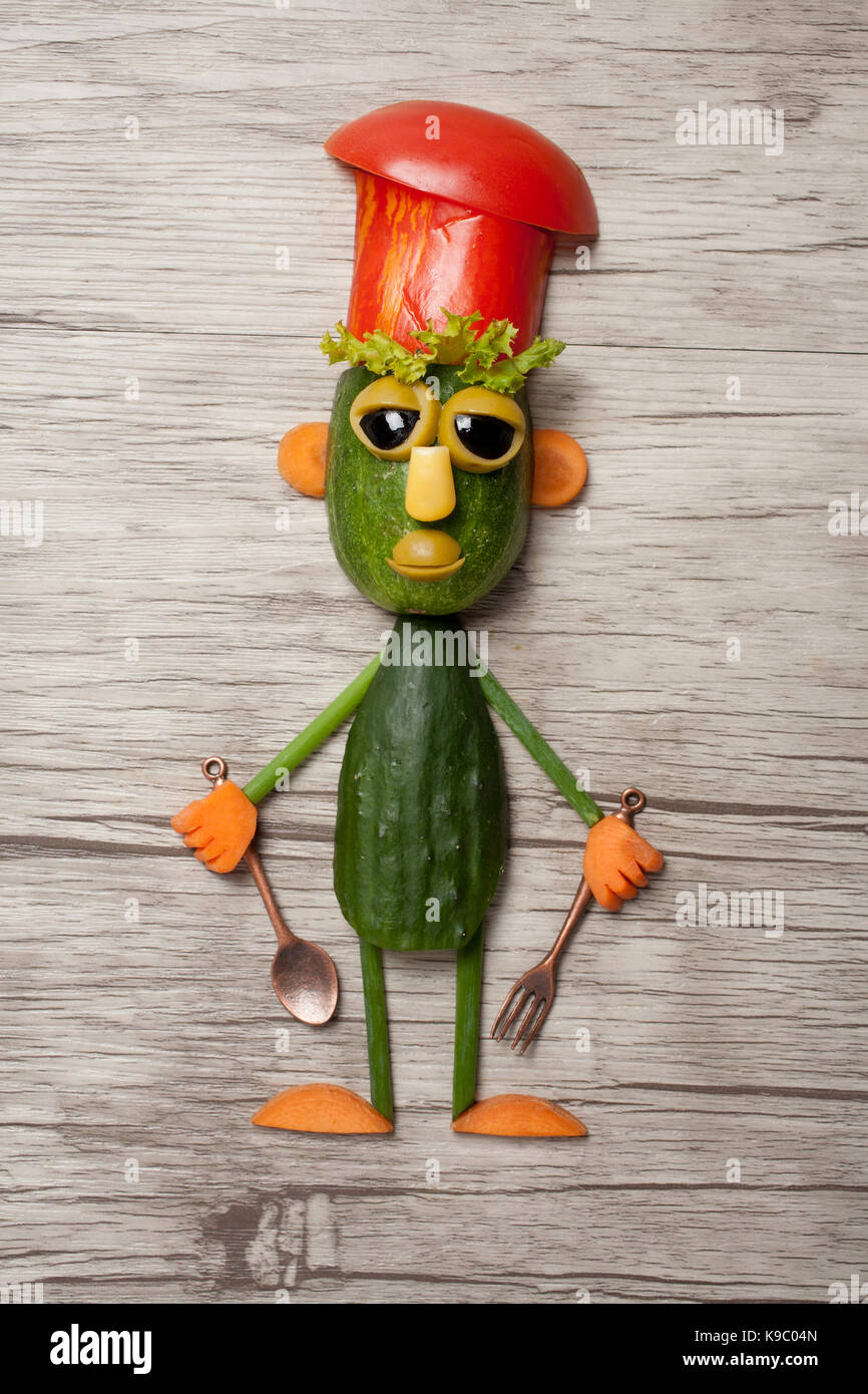 Funny cucumber chief made on wooden background Stock Photo