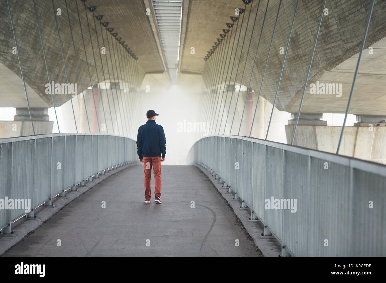 Man on the footbridge under highway bridge in mysterious morning fog. Prague, Czech Republic Stock Photo