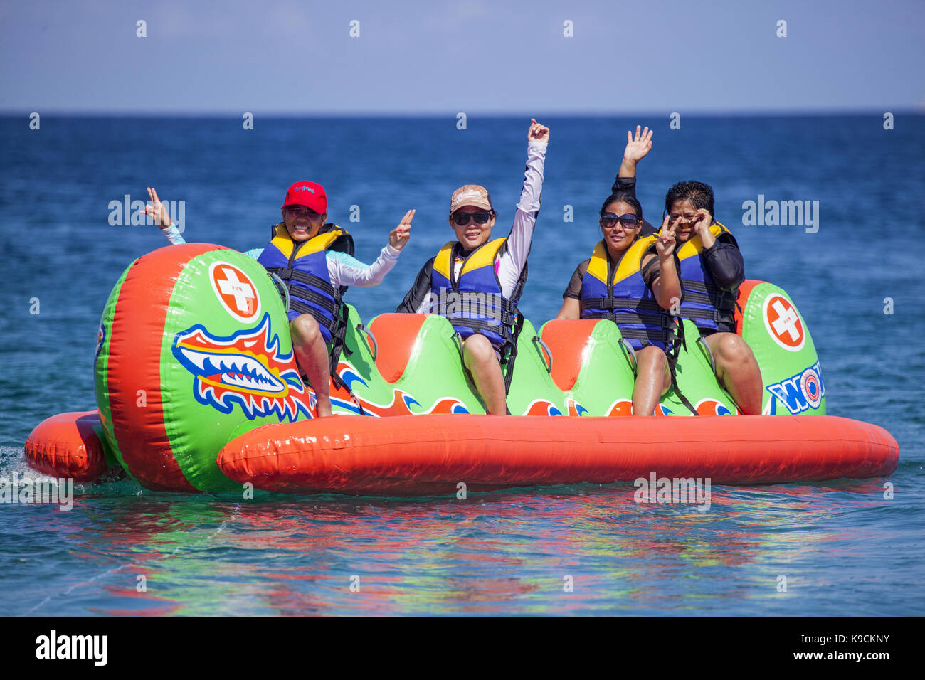 Filipino women ride a dragon banana boat in the Verde Island Passage off White Beach in Puerto Galera, Oriental Mindoro Island, Philippines. Stock Photo