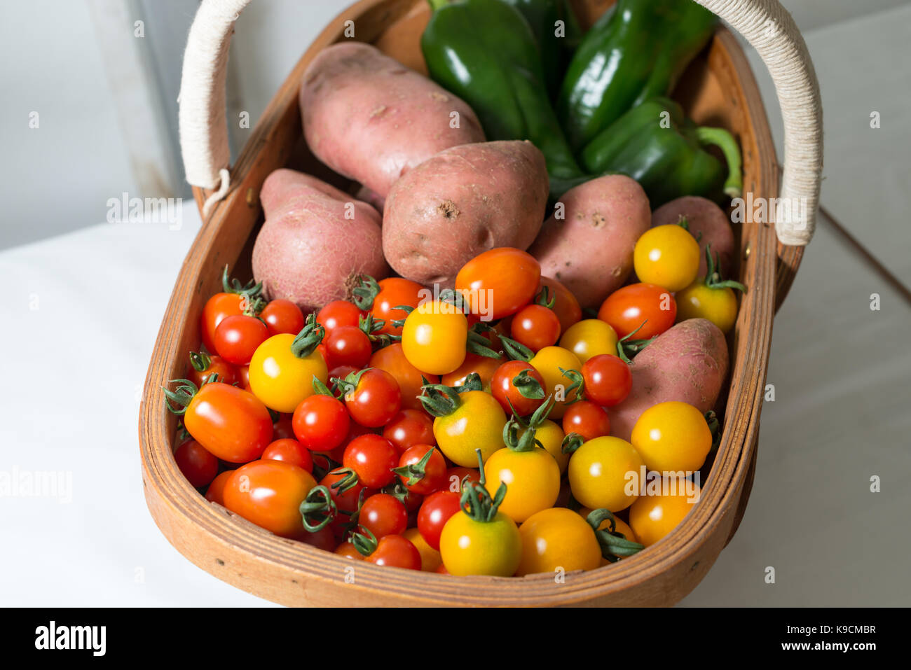 Fresh tomatoes, potatoes and green peppers in a trug and on display at