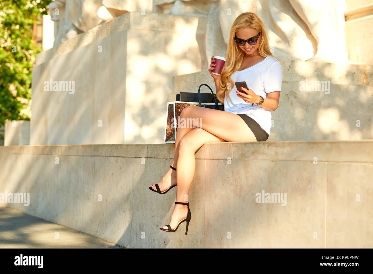 A beautiful young woman sitting on the patten of a statue wearing high