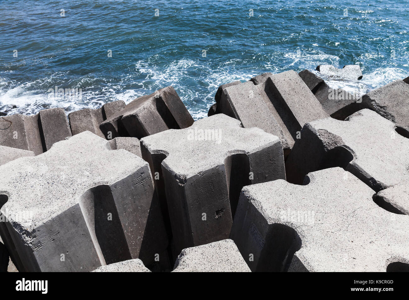Rough concrete blocks as a part of breakwater structure for protection from ocean storm waves Stock Photo