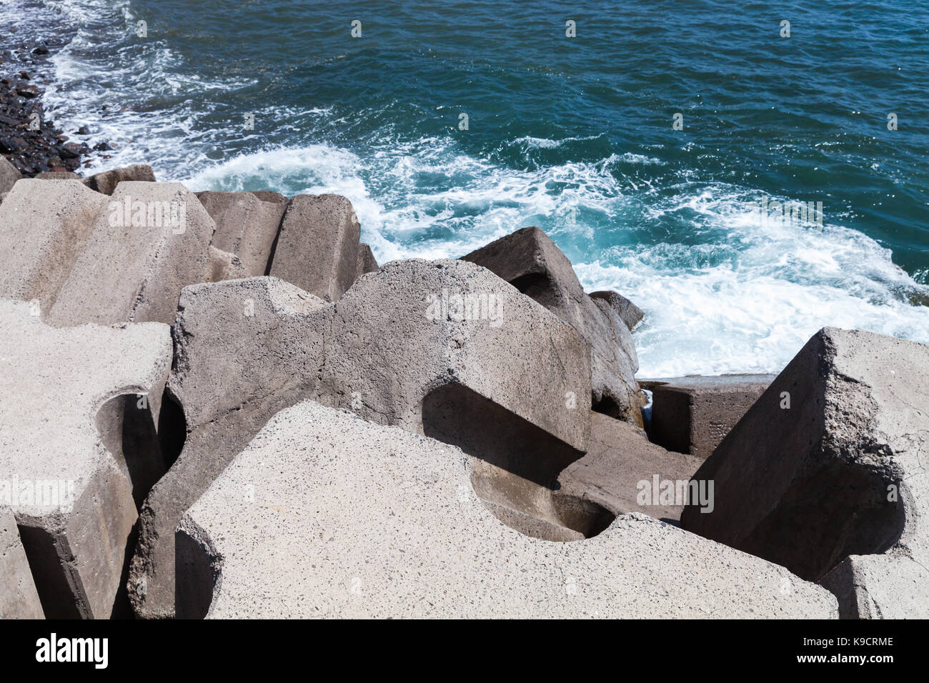 Massive concrete blocks as a part of breakwater structure for protection from ocean storm waves Stock Photo