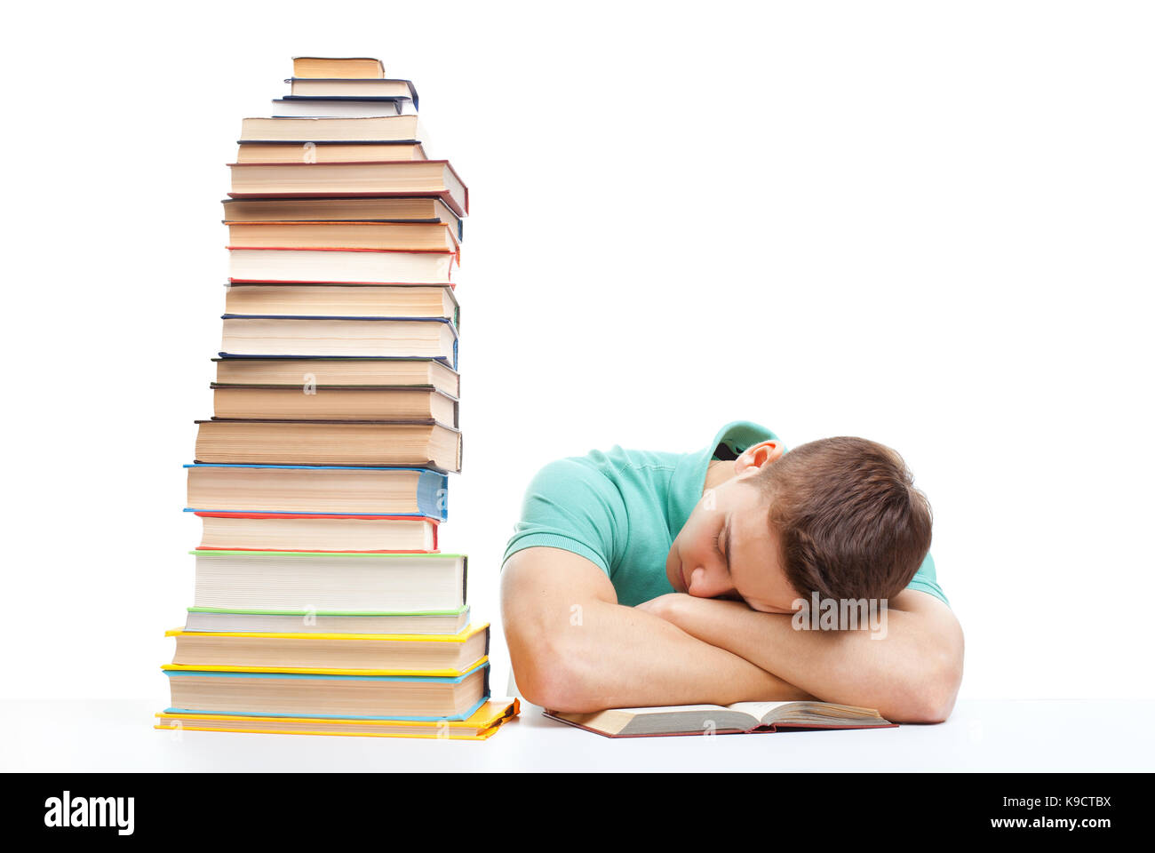Sleeping student sitting at the desk with high books stack isolated on ...