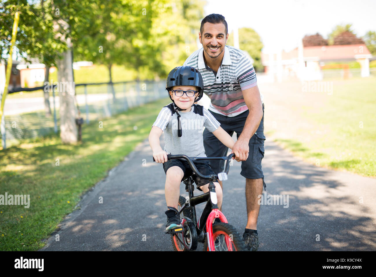 A Father Teaching Son To Ride Bicycle Stock Photo