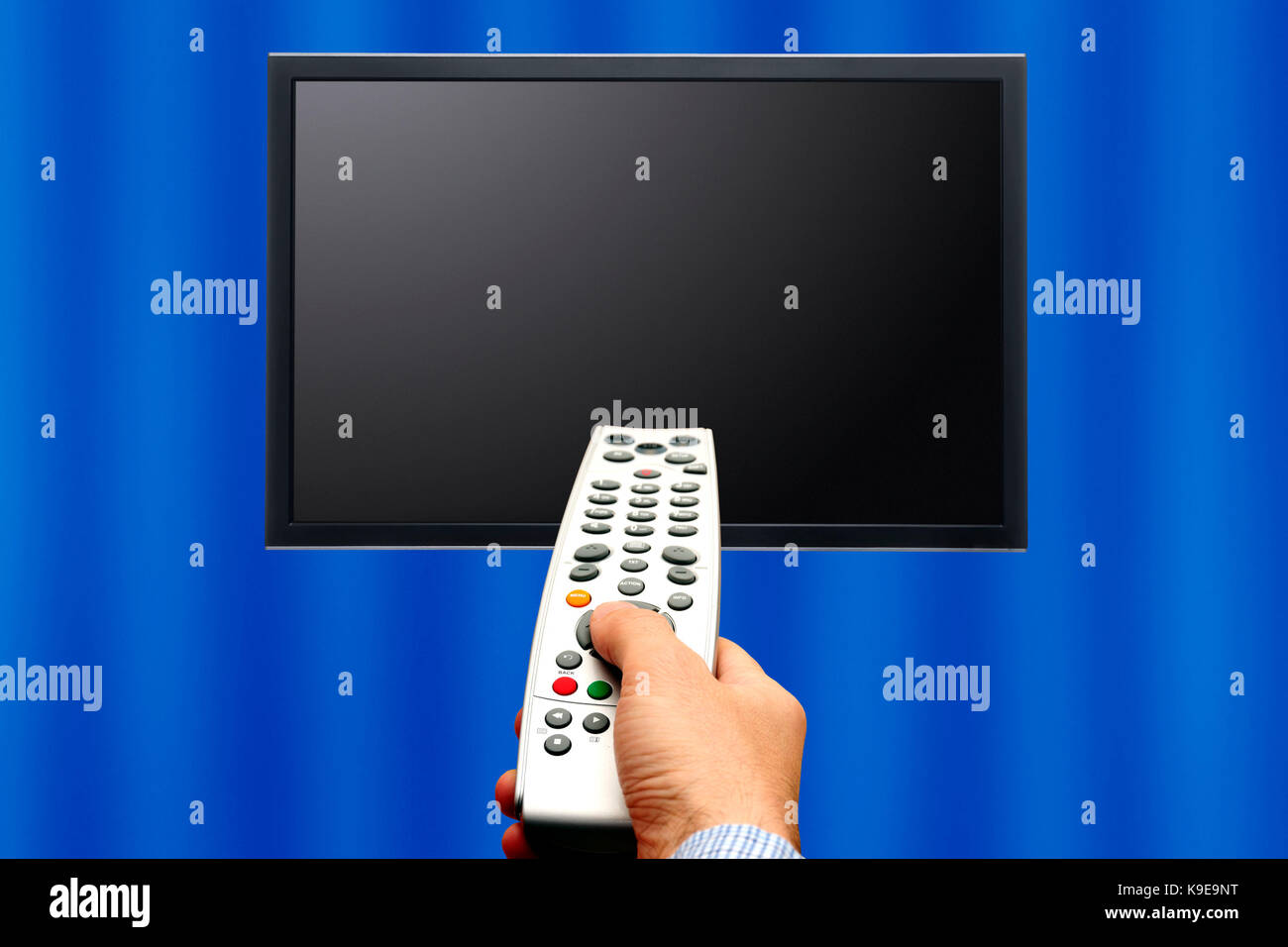 male hand holding a remote control pointed a tv screen Stock Photo