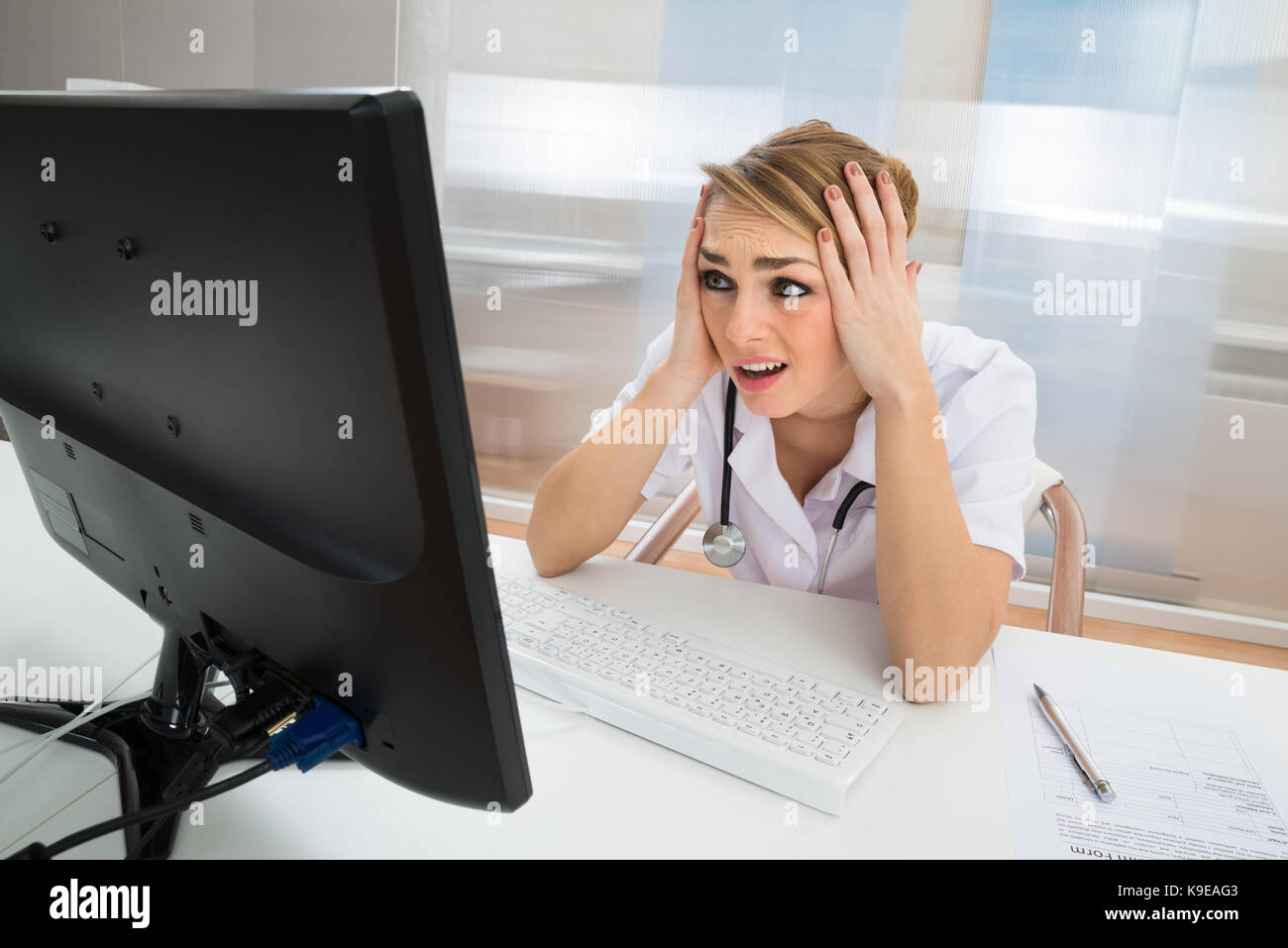 Young Female Worried Doctor Looking At Computer In Clinic Stock Photo