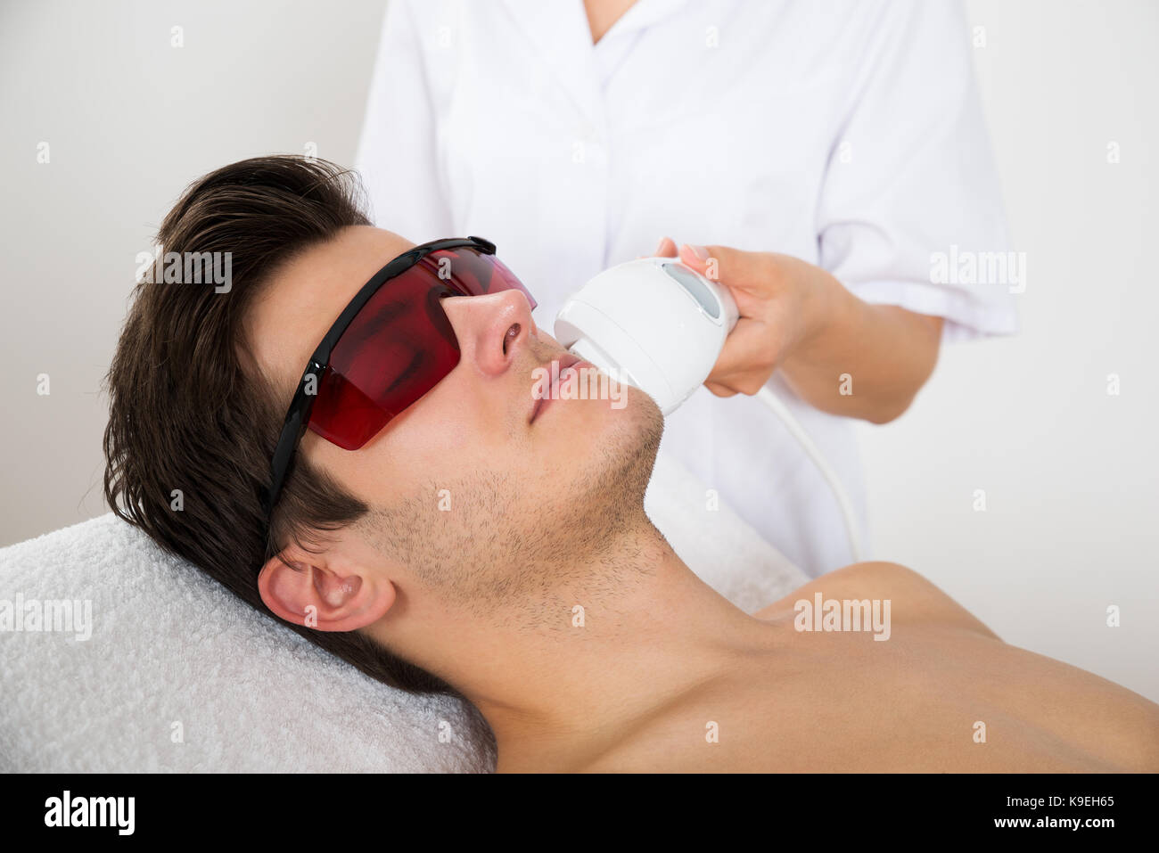 Young Man Receiving Laser Hair Removal Treatment At Beauty Center