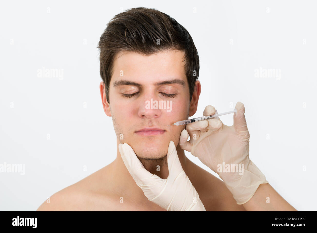 Close-up Of Doctor Hands Injecting Botox Injection In Man Face Stock Photo