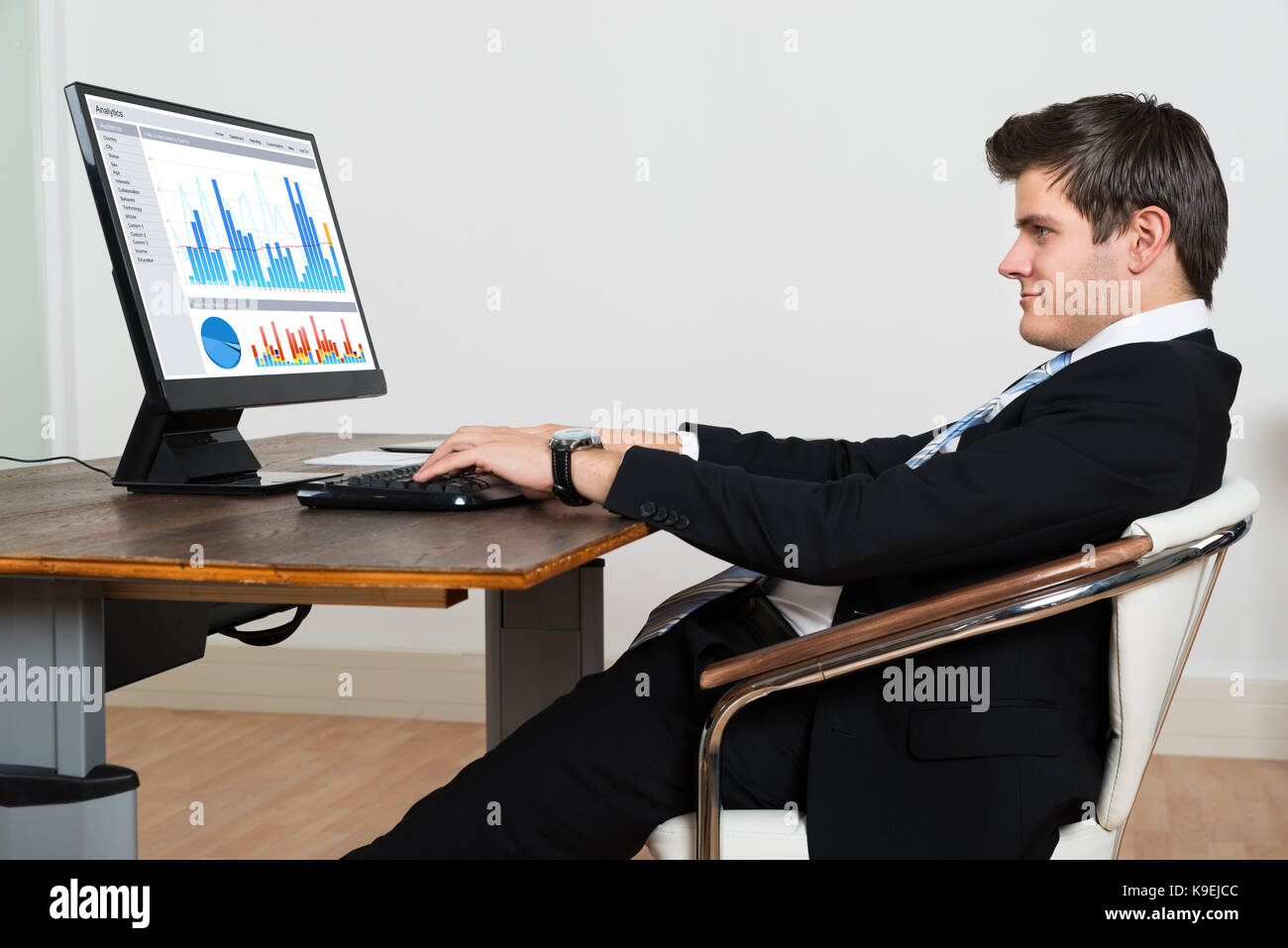 Young Businessman Leaning Back In His Chair While Analyzing Graph On