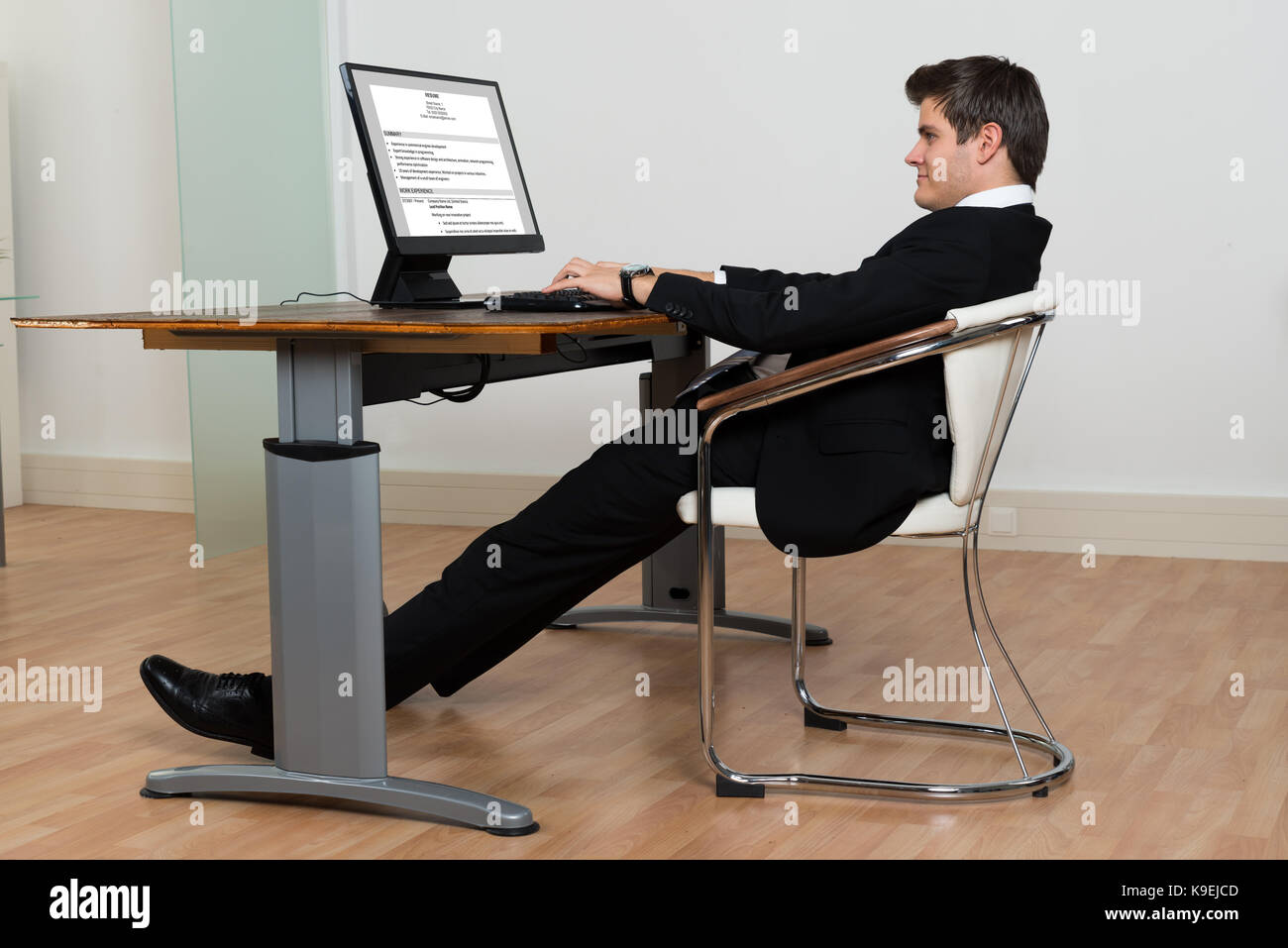 Businessman Leaning Back In His Chair While Working On Computer In Modern Office Stock Photo Alamy