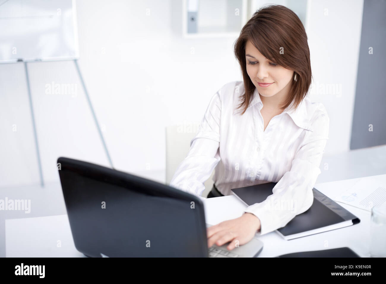 Portrait of beautiful young smiling business woman working on a laptop ...