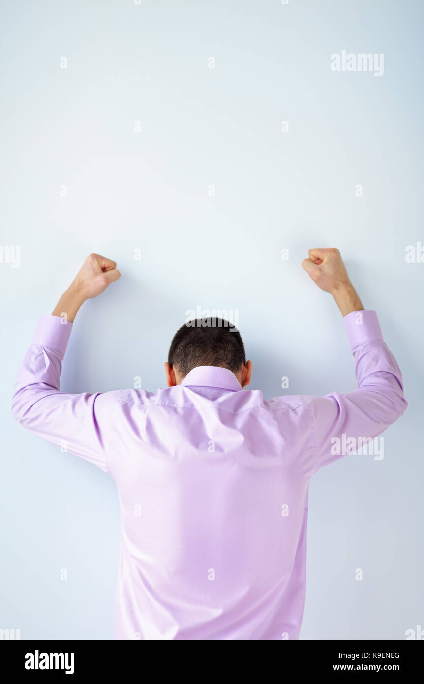 Back view of stressed business man with hands up against the wall Stock Photo